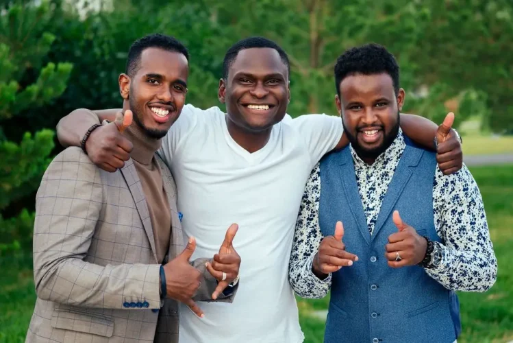 a group of three black men in stylish suits a meeting in a summer park. African-Americans friends hispanic businessman greeting pose outdoors